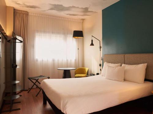 马德里Ibis Madrid Aeropuerto Barajas的配有一张床和一把椅子的酒店客房