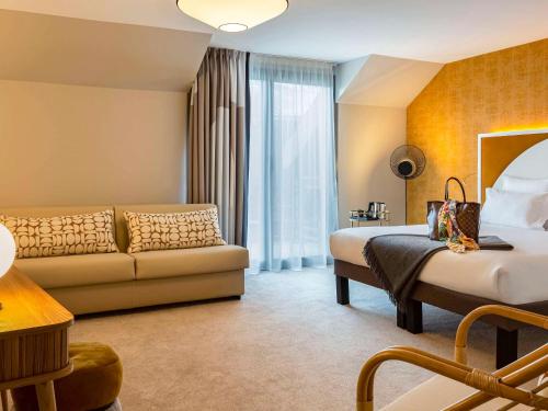 圣热尔韦莱班Le Saint Gervais Hotel & Spa Handwritten Collection的酒店客房设有一张沙发和一张床