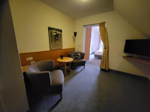 塞芬索内酒店的客厅配有桌椅和电视。