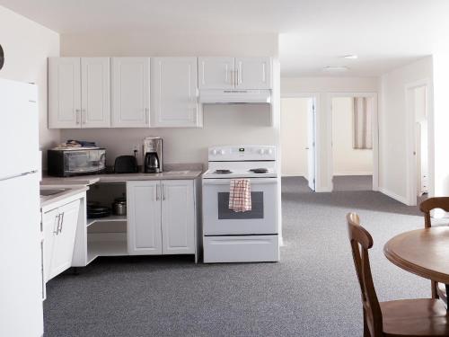 Kirkland LakeProspectors Inn的厨房配有白色橱柜、炉灶和桌子。