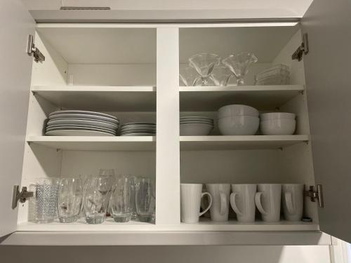 利物浦Dinorwic Lodge的白色的橱柜,装满了碗碟和玻璃杯