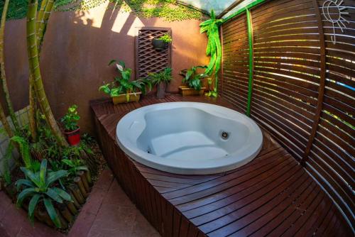马利西亚斯Hotel Canto do Rio Maresias的木甲板上的浴缸,种植了盆栽植物