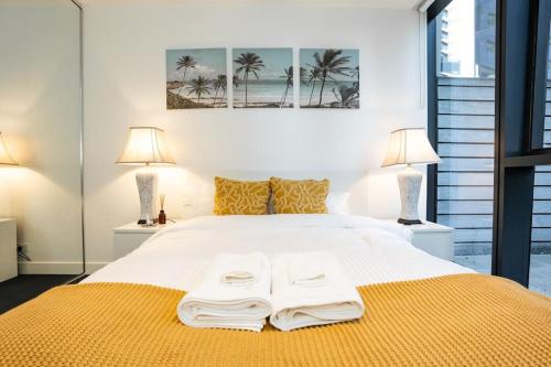 墨尔本2 BD Luxury apartment at heart of Docklands with 85" flat TV & Free Carpark的一间卧室配有一张带两盏灯的大型白色床。