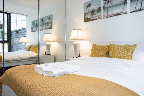 墨尔本2 BD Luxury apartment at heart of Docklands with 85" flat TV & Free Carpark的一间卧室配有一张带白色床单和两盏灯的床。