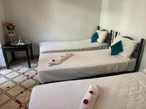 马拉喀什HOTEL EL AMAL的带三张床和一张桌子的房间
