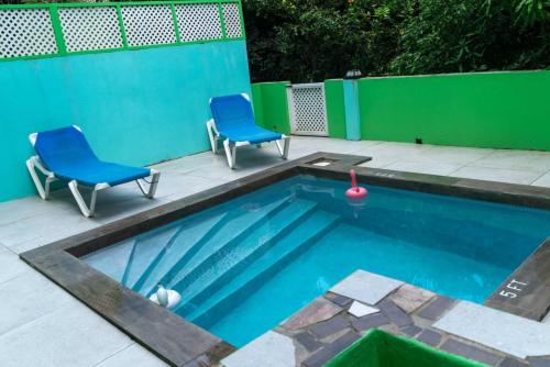 卡斯特里Bougainvillea Apartments的一个带2把蓝色椅子的游泳池和一个游泳池