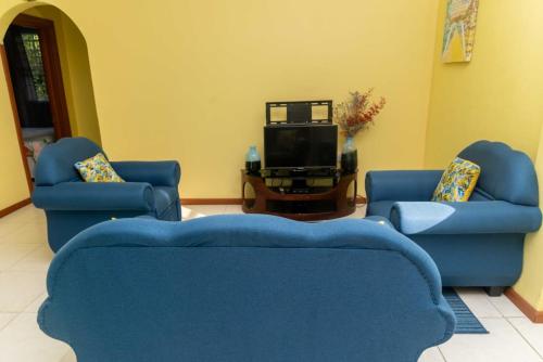 卡斯特里Bougainvillea Apartments的客厅配有2把蓝色椅子和电视