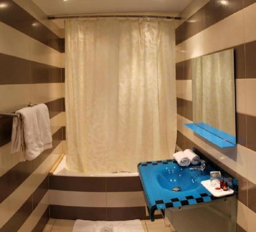 El MadaniaHOTEL IKRAM EL DHAYF的浴室配有蓝色水槽和浴缸。