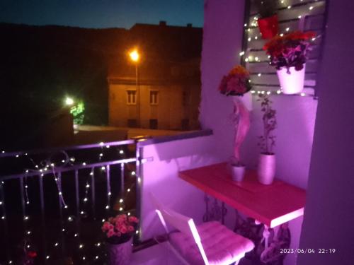 新鲁达Apartament Centrum Nowa Ruda的紫色客房 - 带一个带桌子和鲜花的阳台