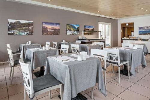 洛迦诺杜拉克酒店的用餐室配有桌子和白色椅子