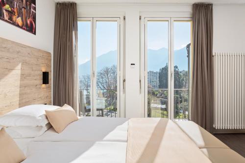 洛迦诺杜拉克酒店的卧室设有白色的床和大窗户