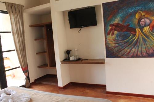 帕伦克帕伦克阿克斯坎酒店的卧室配有绘画和壁挂式电视
