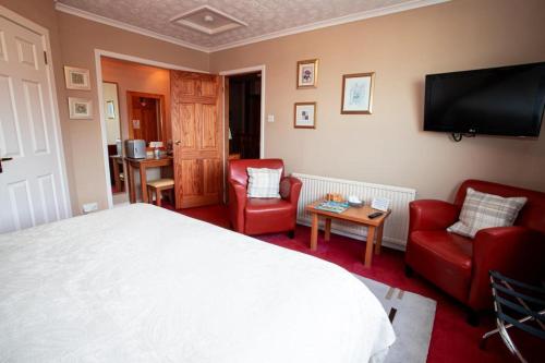奈恩Fonthill Bed and Breakfast Nairn的一间卧室配有一张床、两把椅子和一台平面电视