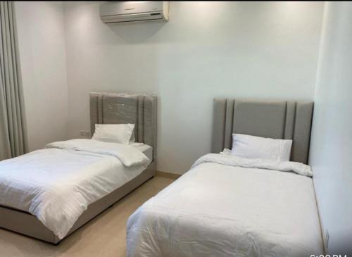 利雅德Alwaha-Appartement的配有白色床单的客房内的两张床