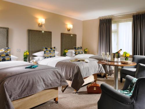 都柏林赫尔伯特山酒店的酒店客房带两张床和一张桌子以及椅子。