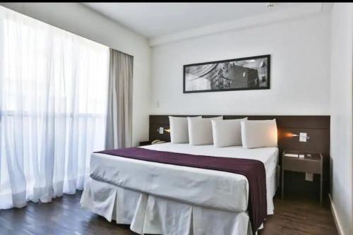 贝洛奥里藏特Apartamento Completo ao lado da lagoa da Pampulha的酒店客房配有一张带白色枕头的大床