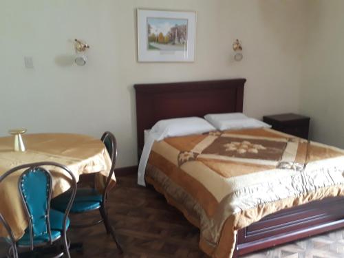 洛哈El Cardenal Hotel的卧室配有一张床和一张桌子及椅子