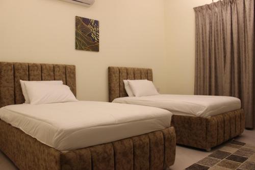 Al Ḩuwaylأمجاد للشقق الفندقية的两张睡床彼此相邻,位于一个房间里