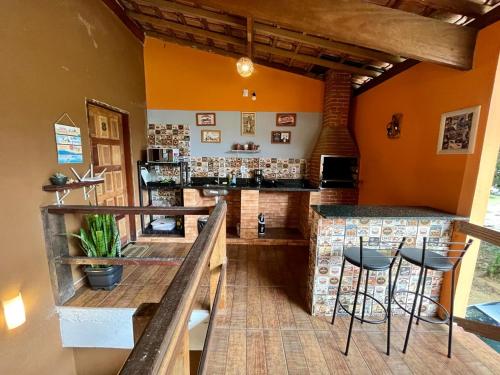 特林达德Pousada Gaivotas的一间酒吧,房间拥有橙色的墙壁和凳子
