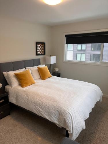 温尼伯Cozy Haven的卧室配有带橙色枕头的大型白色床