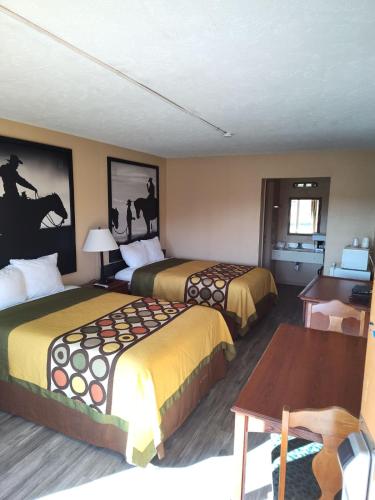 朗维尤Arya Inn & Extended Stay的酒店客房设有两张床和一张桌子。