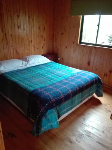 普孔Arcoiris Cabañas的一间卧室配有一张带蓝色毯子的床