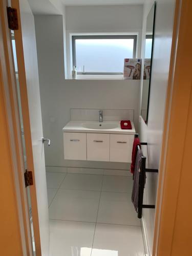 奥克兰Te Rukutai的白色的浴室设有水槽和窗户。