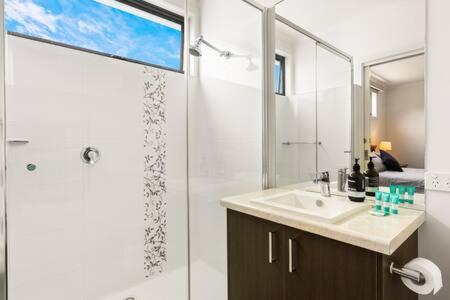 卡尔斯5BR Modern Beach House Oasis的带淋浴、盥洗盆和镜子的浴室