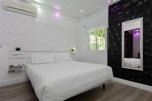 马拉加Malaga Chic jacuzzi y playa的白色的卧室配有白色的床和镜子
