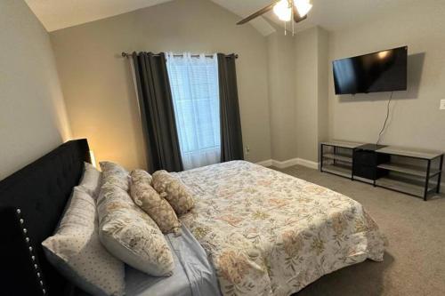 康科德Spacious 3-Bedroom Modern Home Near CLT Motor Speedway的一间卧室配有一张床、一张沙发和一台平面电视。