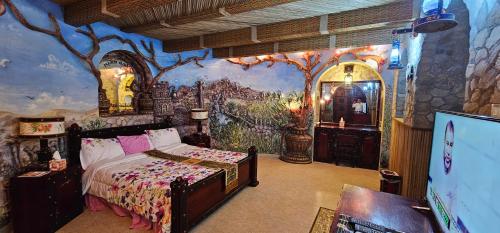 八田Fort Mughaibar Resort的卧室配有一张床,墙上挂有绘画作品
