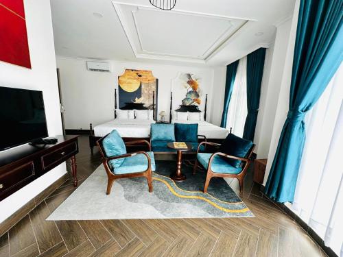 金瓯Khách Sạn The One Hotel 1的一间卧室配有一张床、两把椅子和一台电视