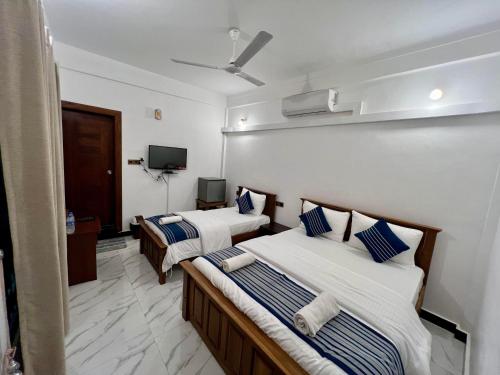 贾夫纳Jaffna Inn的酒店客房设有两张床和一台平面电视。