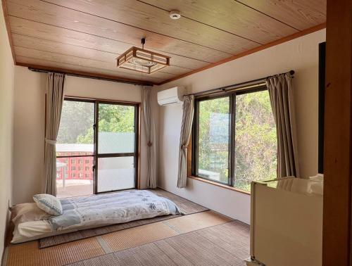 南城ビーチサイドペンションみーばる的一间卧室设有一张床和两个窗户。