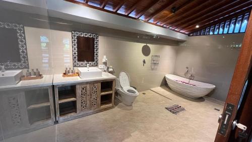 苏卡瓦提罗雅妮别墅的一间带两个盥洗盆、浴缸和卫生间的浴室