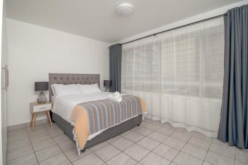 德班Wavecrest 101 Holiday Apartment的一间卧室设有一张大床和一个窗户。