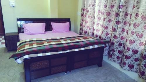 西姆拉The Breeze Homestay的一间卧室配有带粉红色枕头和窗帘的床