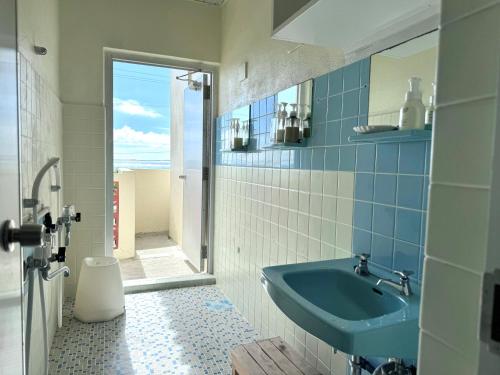 南城ビーチサイドペンションみーばる的浴室设有蓝色水槽和镜子
