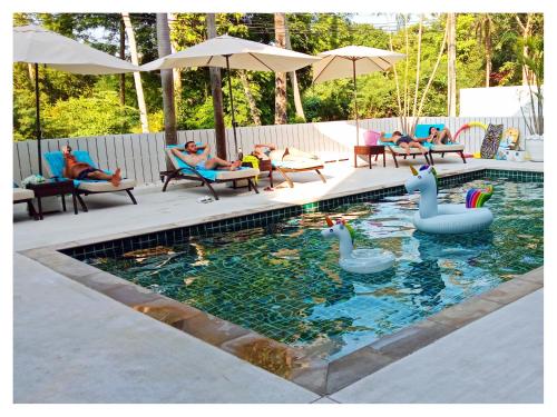 湄南海滩Ampha Place Hotel的游泳池,有天鹅,有椅子的人