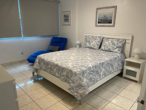 圣胡安Isla Verde Beach Modern apartment的一间卧室配有一张床和一张蓝色椅子