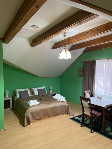 德鲁斯基宁凯吉瑞瓦酒店的一间卧室设有绿色的墙壁、一张床和一张桌子