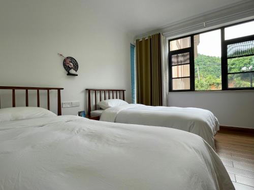 Liyang千岛湖月下民宿的一间卧室设有两张床和窗户。