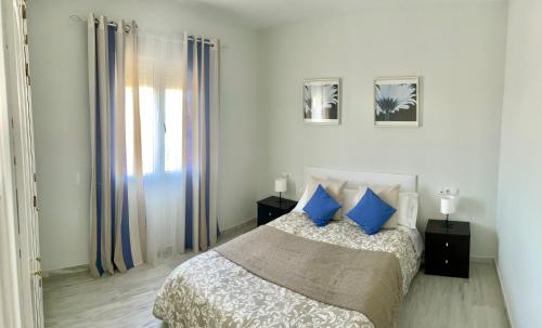 博尔穆霍斯Apartamento Liru Bormujos 2, a 5 minutos de Sevilla的一间卧室配有一张带蓝色枕头的床