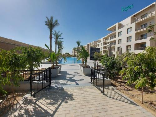 开罗Alumia Marigold Suite 3BR Apt Pool Access的棕榈树建筑前的走道