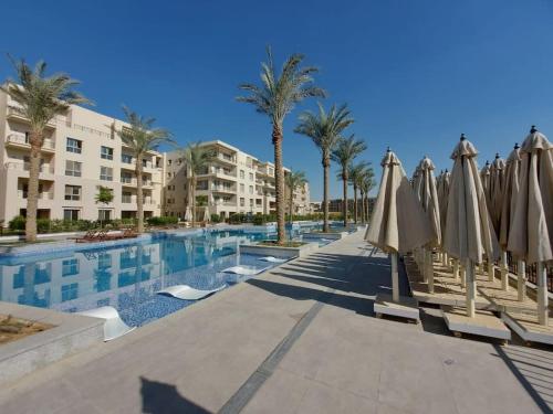 开罗Alumia Marigold Suite 3BR Apt Pool Access的一座带遮阳伞的游泳池和一座建筑