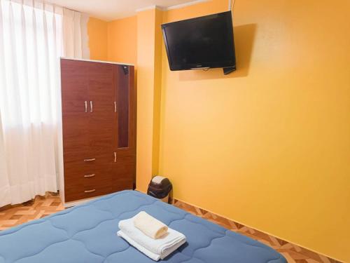 利马A y J Familia Hospedaje的卧室配有一张床,墙上配有电视。