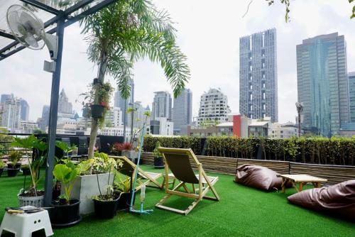 曼谷Hip and funky apartment silom Soi 3, with rooftop view的一个带椅子和植物的庭院,享有城市天际线