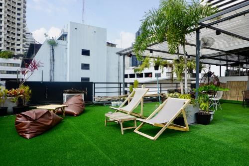 曼谷Hip and funky apartment silom Soi 3, with rooftop view的屋顶上带椅子和草地的天井