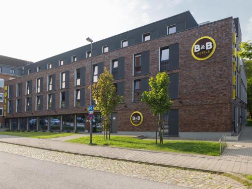 基尔B&B Hotel Kiel-Wissenschaftspark的砖砌的建筑,旁边标有标志