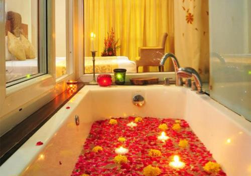 新德里Hotel Palm Do'r Near New Delhi Railway Station的浴室里装满蜡烛和鲜花的浴缸
